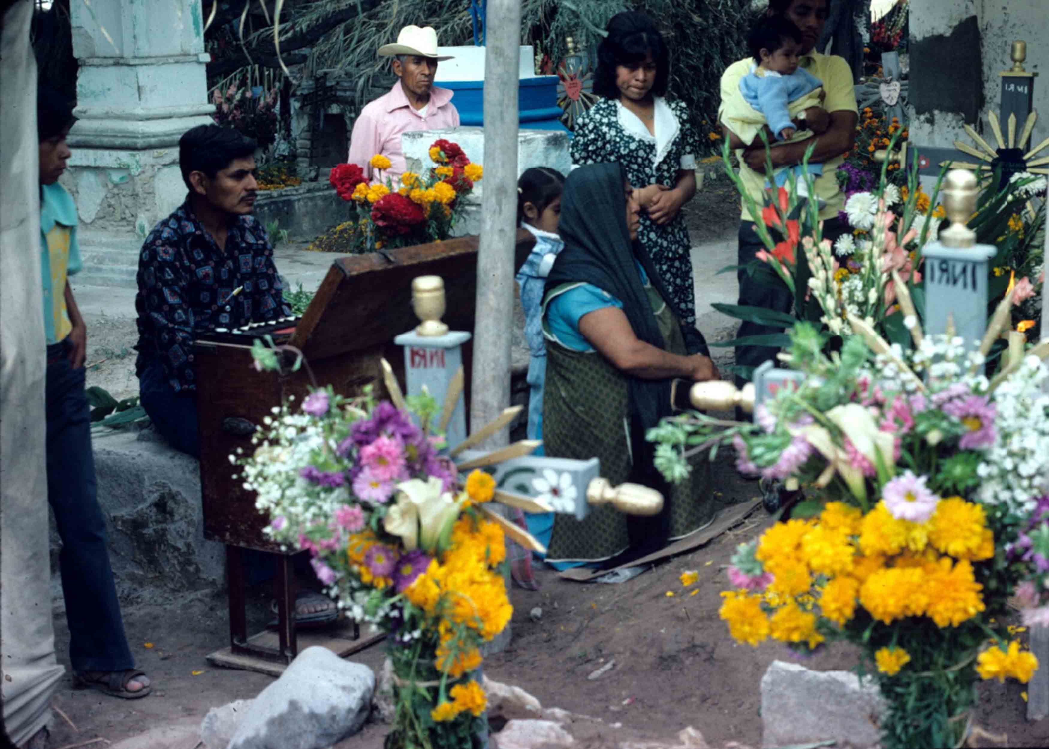 Familie bezoekt een graf op Allerzielen / Día de Muertos. Fotograaf Ted Leyenaar, 1975.   